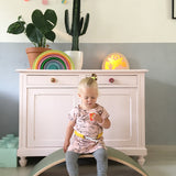 Child sitting on a Wobbel Original beech balance board with wool felt backing in a playroom setting.