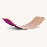 Wobbel Original beech balance board with raspberry wool felt backing on a plain background