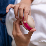 A child holding a Wobbel Candy Macaron in their hands. The Macaron is natural PEFC certified maple and beech wood