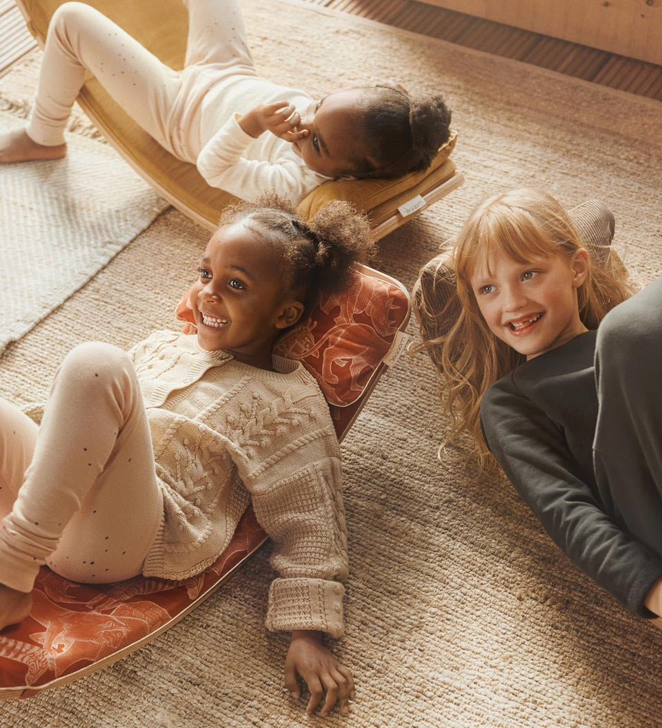 Kids laying on some Wobbel balance boards with different coloured accessory deck cushions and pillows
