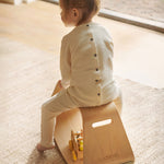 Close up of a young child sat on a plastic-free Wobbel balance box on a grey carpet