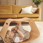 Child laying on their back inside the Wobbel plastic-free wooden Big Up balance box
