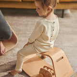 Young girl sat on a Wobbel wooden Up balance box on a grey carpet