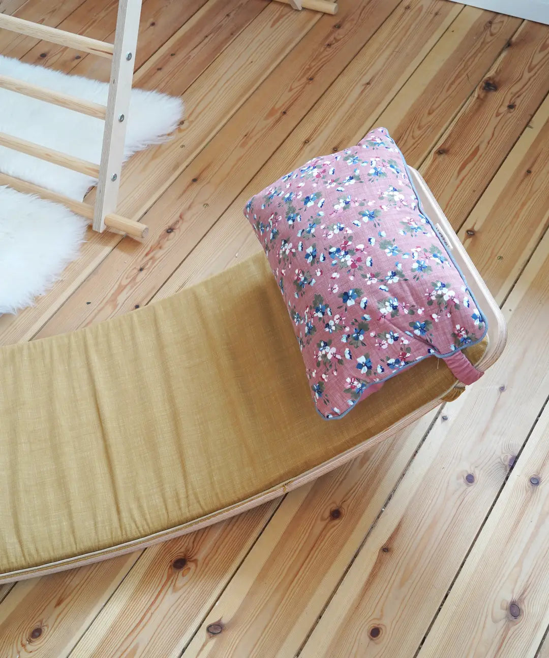 Ochre XL deck on a Wobbel board with a floral pillow on a wooden surface  