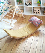 Ochre XL deck on a Wobbel board with a floral pillow on a wooden surface next to a Triclimb in the Babipur playroom 