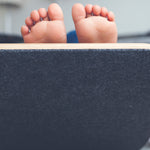 Close up of childs bare feet sticking out of the top of a Wobbel Pro Felt balance board