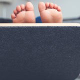 Close up of childs bare feet sticking out of the top of a Wobbel Pro Felt balance board