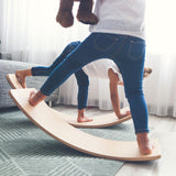 Two children balancing on Wobbel Starter balance boards with felt on a living room carpet