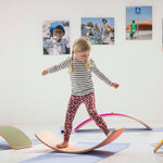 Girl balancing on a Wobbel Beech Wood balance board on a yoga mat
