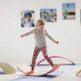Girl balancing on a Wobbel Beech Wood balance board on a yoga mat