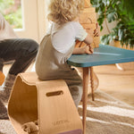 Child sat at a table playing with some wooden toy blocks