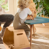 Child sat at a table playing with some wooden toy blocks