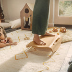 Close up of woman's feet on a Wobbel Sup balance board next to a toddler sat on the floor