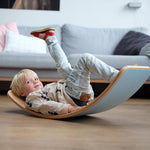 Child laying on a Wobbel XL Beech Wood balance board with Felt in a living room