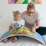 Woman and child reading a book on a Wobbel XL felted board on a bed