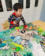 Close up of young boy playing with wooden toy animals on the Wonder Cloths organic cotton into the jungle play cloth