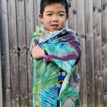Young boy wrapped up in the eco-friendly Wonder Cloths in front of a wooden fence
