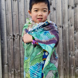 Young boy wrapped up in the eco-friendly Wonder Cloths in front of a wooden fence