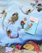 Wondercloths childrens mermaid ocean print play silk laid on the floor with some soft toy mermaids and sea creatures on top