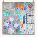 Wonderie Sensory Play Cloth - Around The Kitchen. Looking down on a busy kitchen scene, this play cloth shows a kitchen table with plates and cutlery, a cooking hob, chopping board, sink, toaster and pots and pans.