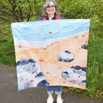 An adult holding up the Wonderie Rock Pool Life Play Cloth to show scale.