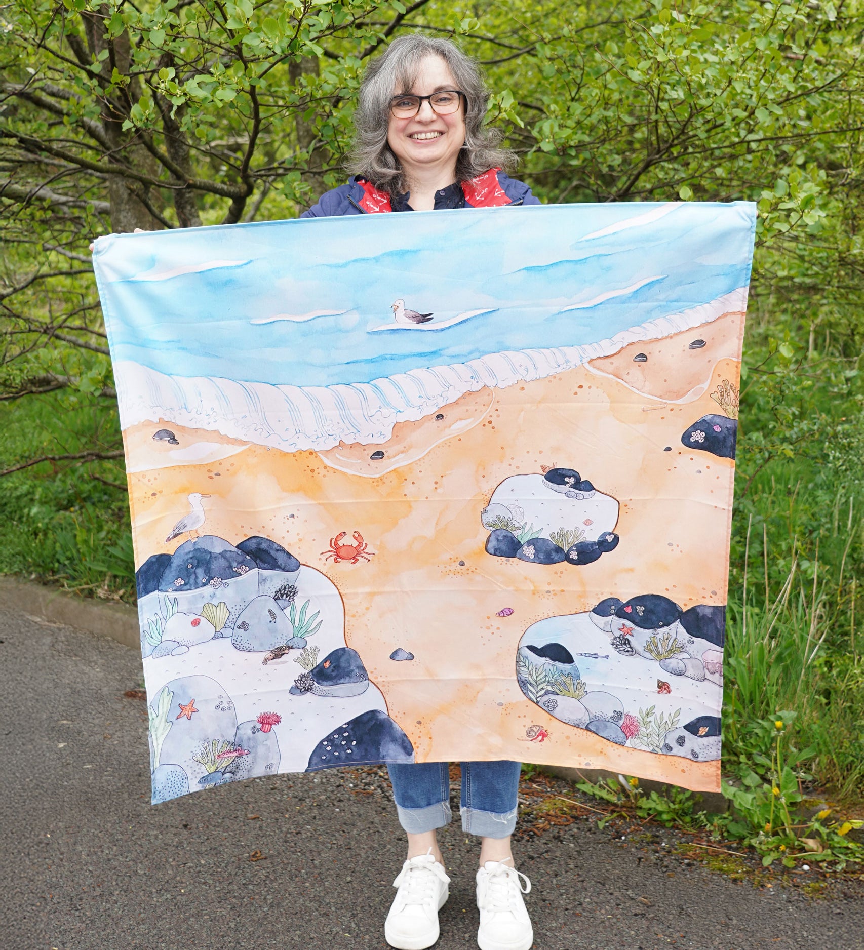 An adult holding up the Wonderie Rock Pool Life Play Cloth to show scale.