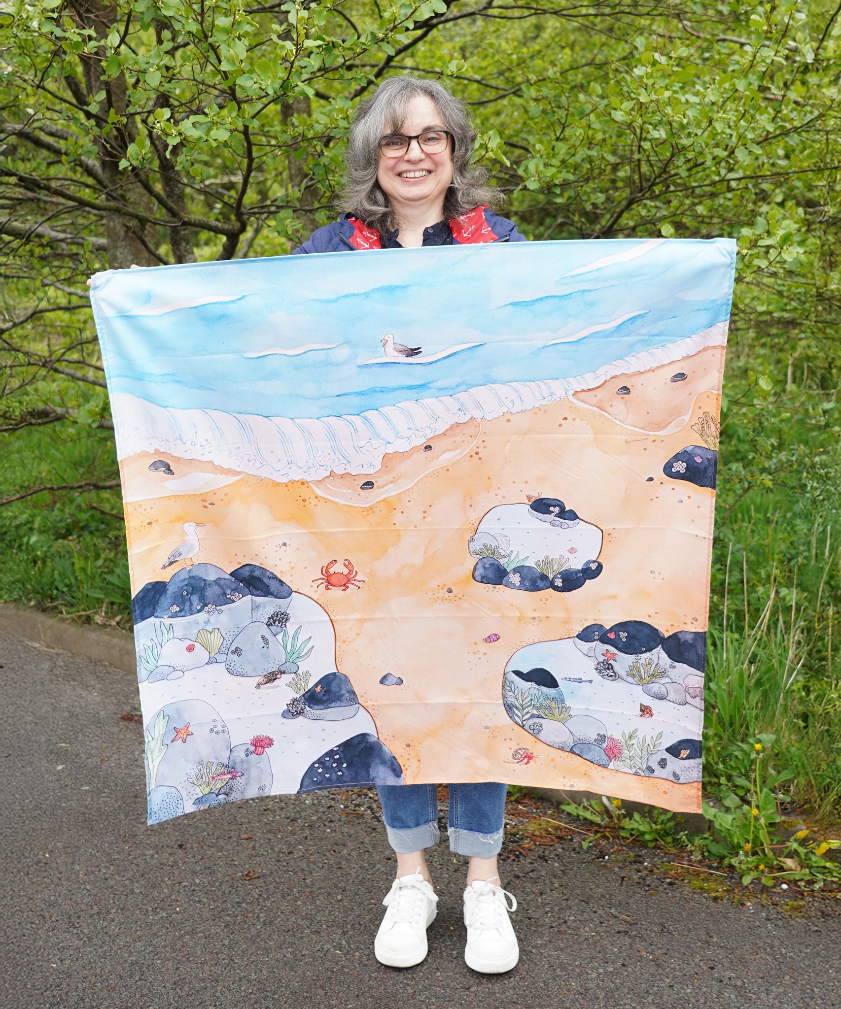 An adult holding up the Wonderie Rock Pool Life Play Cloth to show scale.