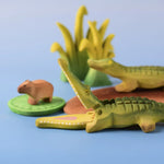 Bumbu Toys' Wooden Crocodile and Baby Crocodile, in a scene with Bumbu's Capybara, Reeds in large and small, and a Lilypad.