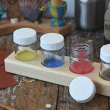 Wooden block holder with 50ml glass jars placed inside with paint in them.  