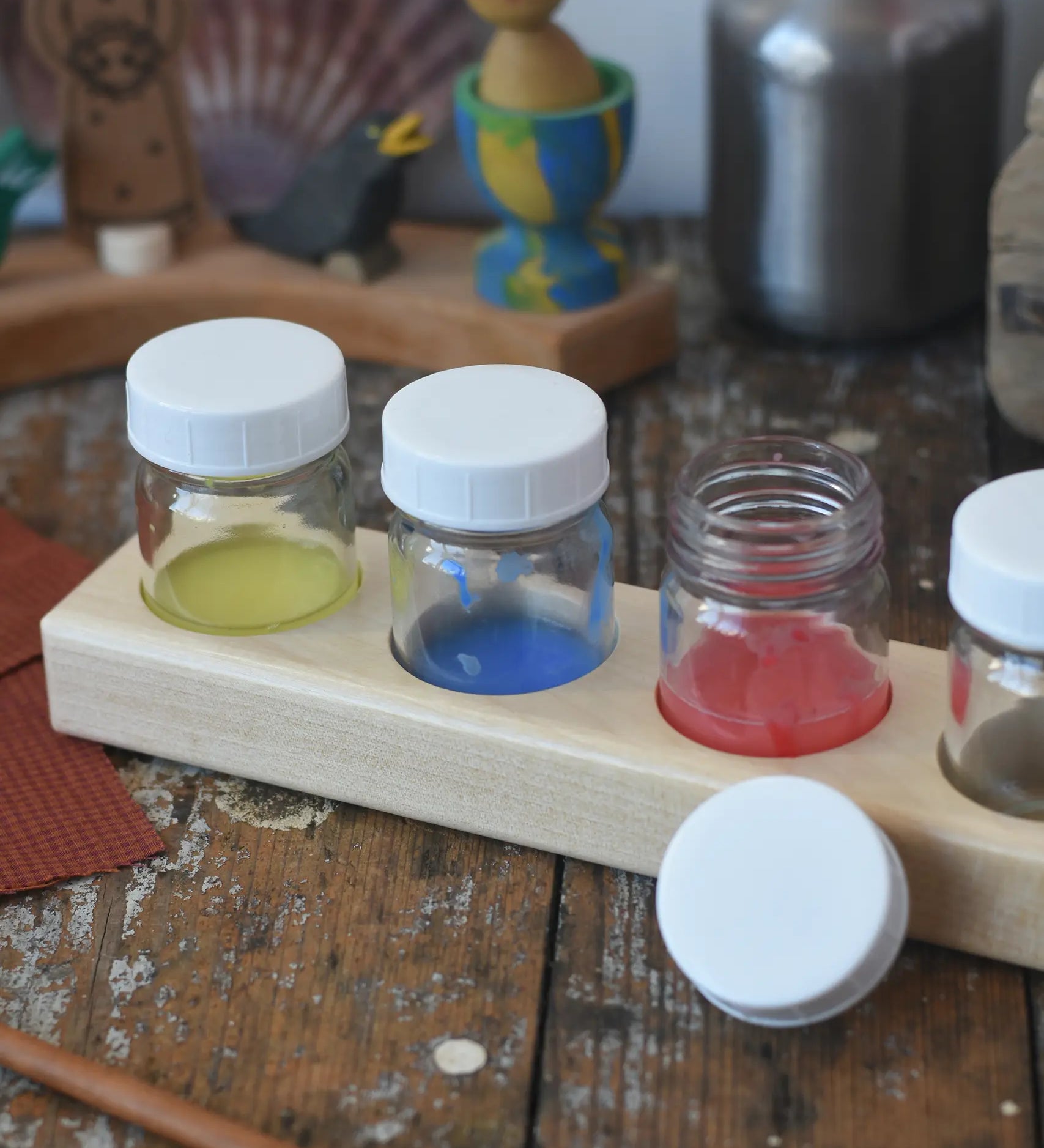 Wooden block holder with 50ml glass jars placed inside with paint in them.  
