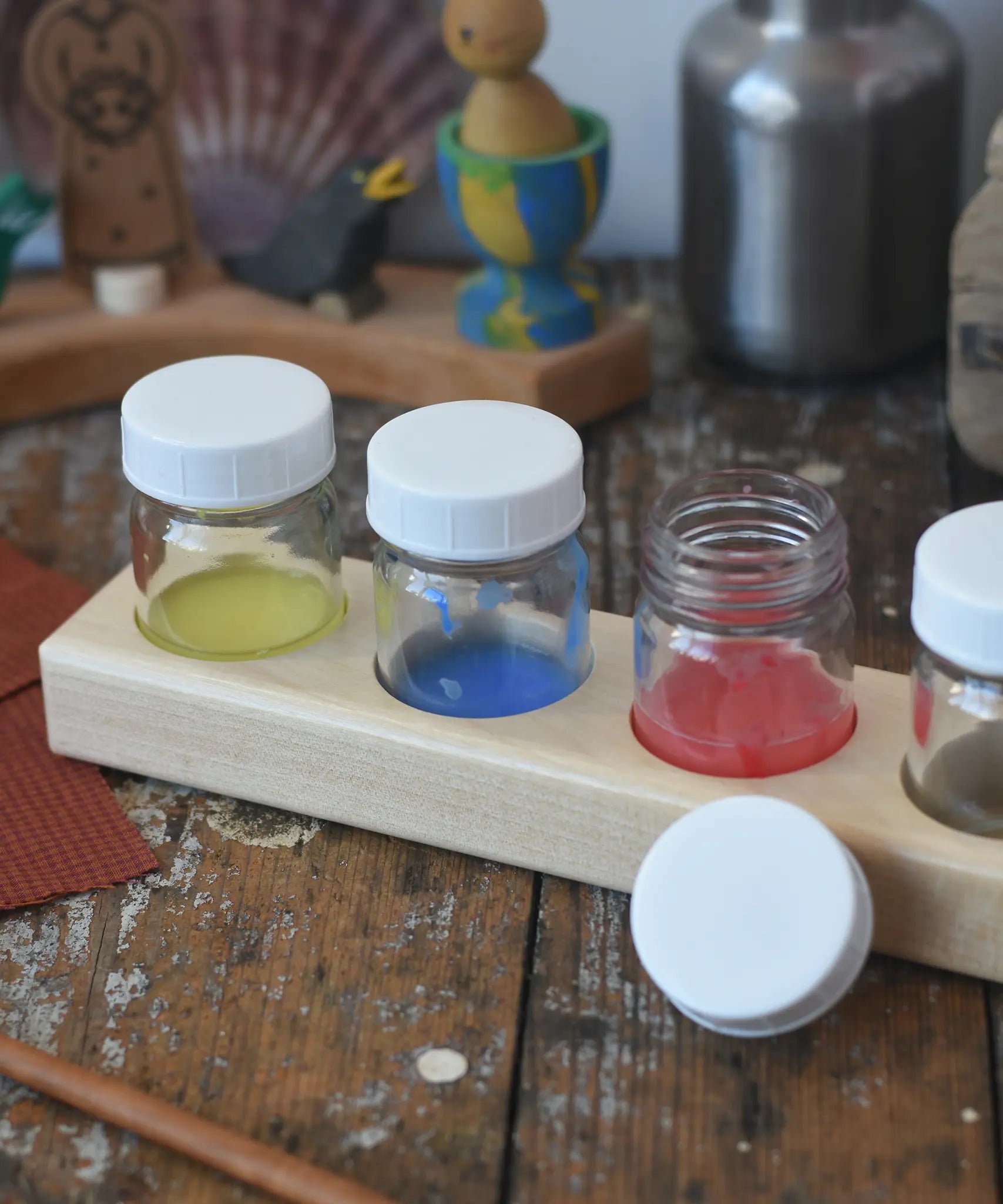 Wooden block holder with 50ml glass jars placed inside with paint in them.  