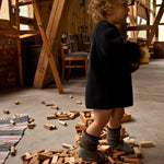 A child walking over blocks from the Wooden Story 54 natural block set.  