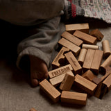 A collection of natural Wooden Story blocks on the floor, a child's foot can be seen besides them.