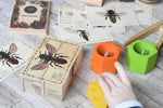 A child playing with the Wooden Story Species of Bees Puzzle Blocks Set alongside The PlanToys Bee hives. 