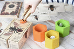 A child playing with the Wooden Story Species of Bees Puzzle Blocks Set alongside The PlanToys Bee hives. 