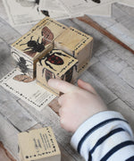 A close up of a child's hand playing with the Wooden Story Species of Bees Puzzle Blocks Set. The blocks have been placed on the corresponding bee card. 