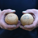 A close up of an adult's hand holding two of the Boules balls in their hands. 