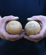 A close up of an adult's hand holding two of the Boules balls in their hands. 