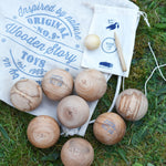 The Wooden Story wooden boules Petanque traditional game set. The pieces from the set have all been placed on top of the cotton drawstring storage bags they come in.  