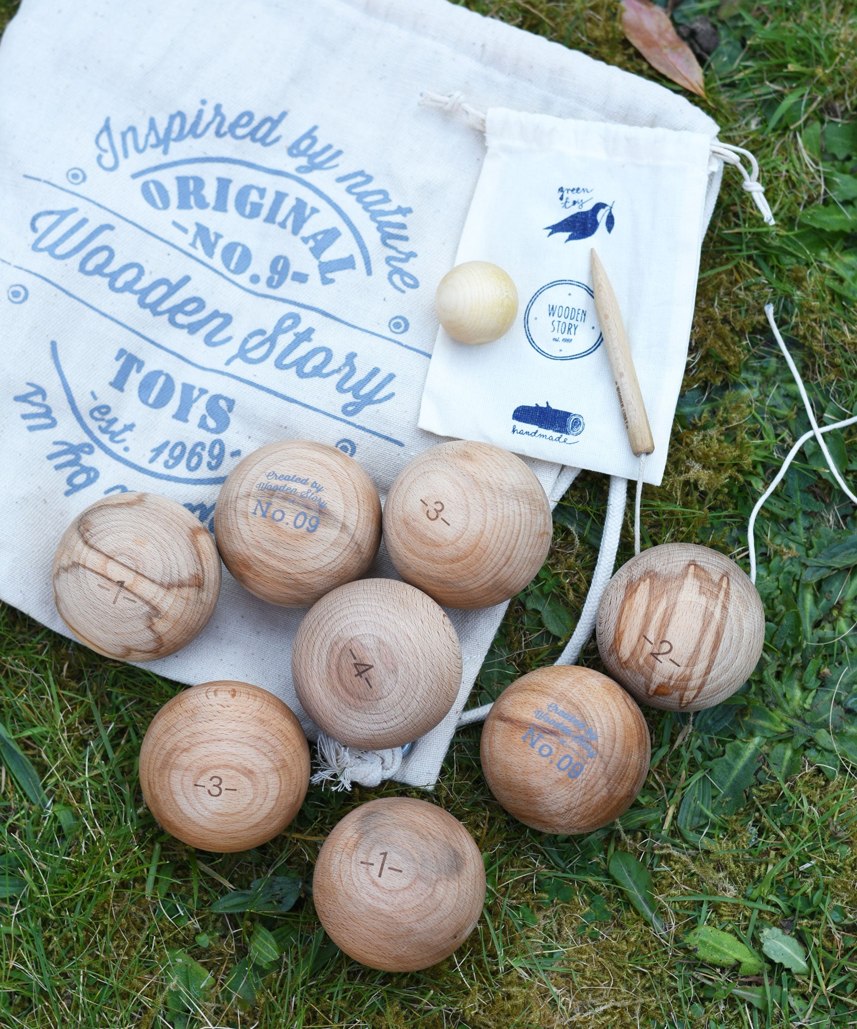 The Wooden Story wooden boules Petanque traditional game set. The pieces from the set have all been placed on top of the cotton drawstring storage bags they come in.  
