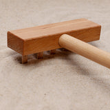 A close up of the wooden taking tool from the Wooden Story Montessori Sand Tray and Accessories. 