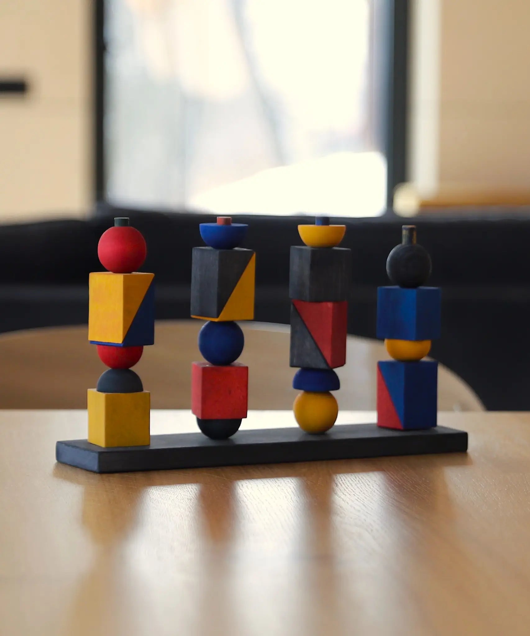 Wooden Story modern stacking toy on a table showing each Bauhaus inspired block stacked on the base