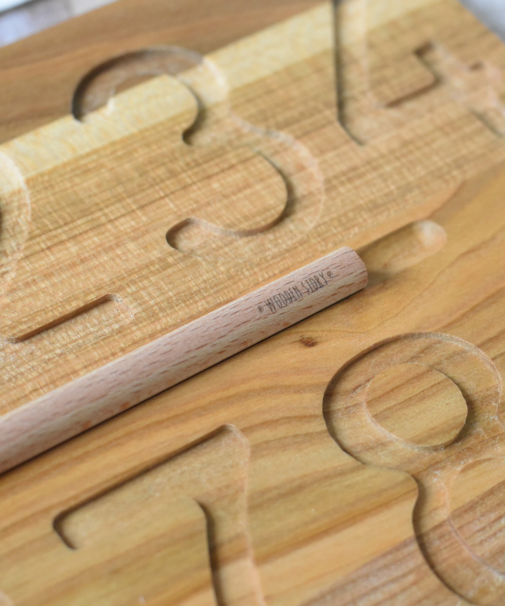 A close up of the Wooden Story logo that's engraved into the wooden pen from the Montessori Number Tracing Board Set. 