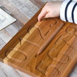A close up of a child's hand using their finger to trace the number 3 on the Wooden Story Montessori Number Tracing Board.