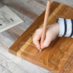 A close up of a child's hand using the wooden pen on the number side of the Montessori Number Tracing Board. 