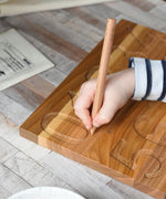 A close up of a child's hand using the wooden pen on the number side of the Montessori Number Tracing Board. 