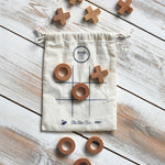 The Wooden Story Tic Tac Toe game with the bag and pieces placed on a wooden surface.