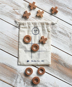The Wooden Story Tic Tac Toe game with the bag and pieces placed on a wooden surface.