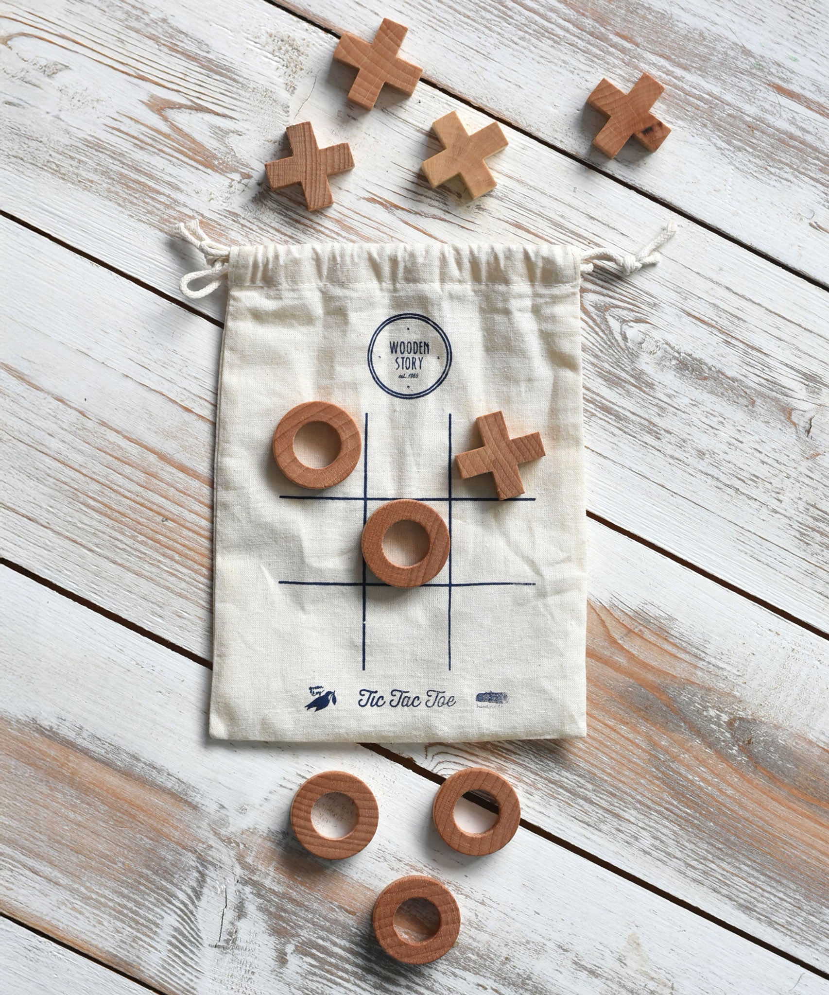 The Wooden Story Tic Tac Toe game with the bag and pieces placed on a wooden surface.