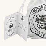 Close up of the Wooden Story Peace & Love Blocks canvas drawstring gift bag and gift-tag.